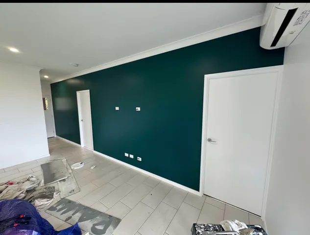 Deep teal accent wall in a modern room with white doors and light tiled flooring.